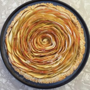 A baked tart, photographed from above, filled with concentric rings of thinly-sliced apple.